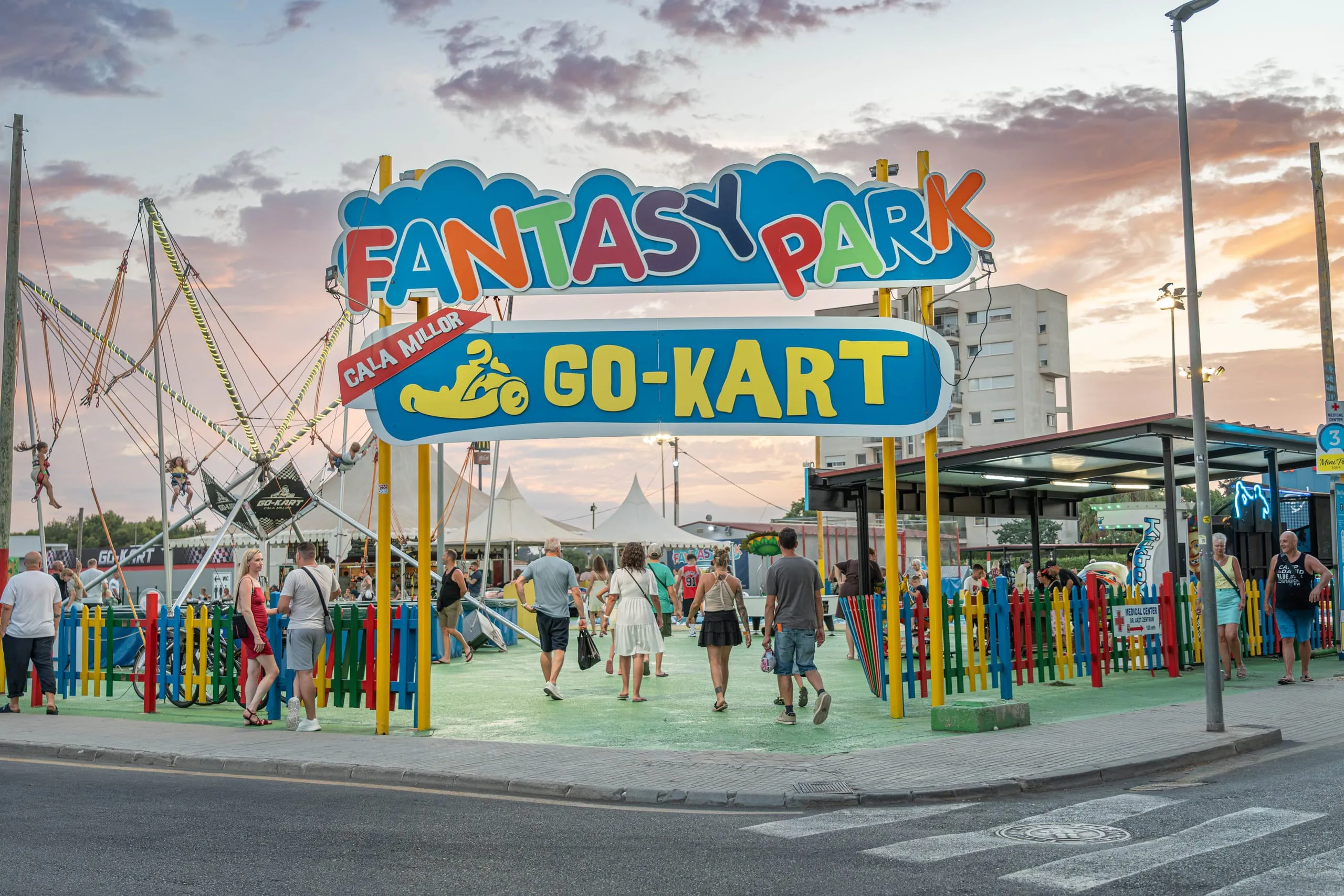 Entrada de Fantasy Park & Go Kart Cala Millor al atardecer, con familias entrando al parque