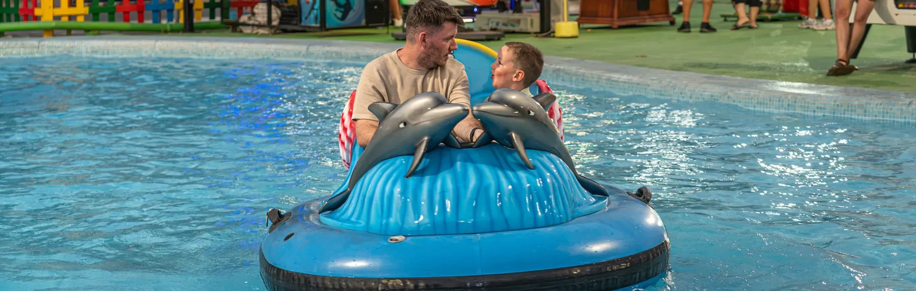 Padre e hijo en una barca eléctrica en la piscina del parque